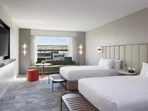 a hotel room with two beds and a couch at PARKROYAL Melbourne Airport in Melbourne