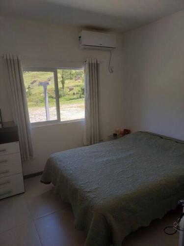 um quarto com uma cama em frente a uma janela em Sítio dos Gaitas Vila Hoffmann em São Pedro de Alcântara