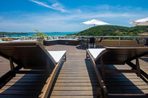 a boardwalk with benches and tables and the ocean at Pousada e Spa Villa Mercedes by Latitud Hoteles in Búzios
