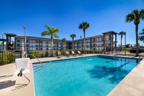 a pool at a hotel with chairs and palm trees at SureStay by Best Western Clermont Theme Park West in Kissimmee