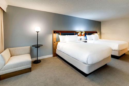 a hotel room with two beds and a chair at Sonesta Select San Francisco Airport Oyster Point Waterfront in South San Francisco
