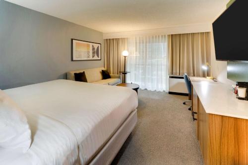 a hotel room with a white bed and a couch at Sonesta Select San Francisco Airport Oyster Point Waterfront in South San Francisco