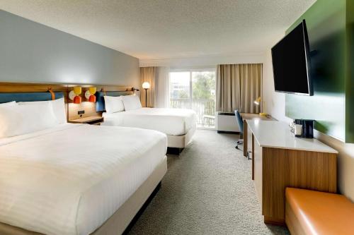 a hotel room with two beds and a flat screen tv at Sonesta Select San Francisco Airport Oyster Point Waterfront in South San Francisco