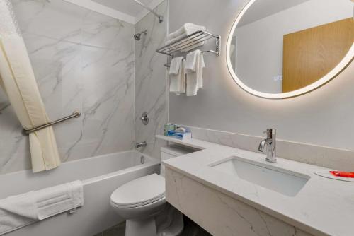 a bathroom with a sink and a toilet and a mirror at SureStay Plus by Best Western Brooks in Brooks