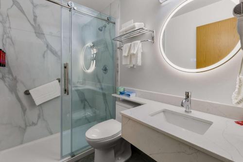 a bathroom with a shower and a toilet and a sink at SureStay Plus by Best Western Brooks in Brooks