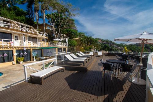 a deck with chairs and tables and an umbrella at Pousada e Spa Villa Mercedes by Latitud Hoteles in Búzios