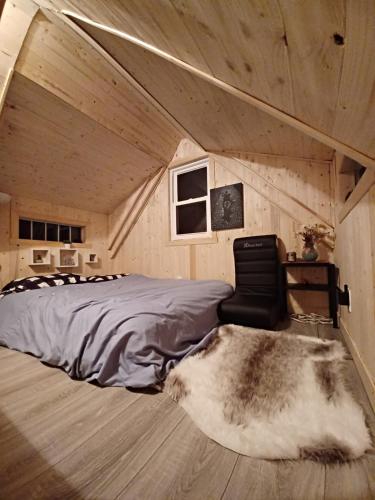 1 dormitorio con 1 cama, 1 silla y 1 alfombra en Le petit Cottage du Grand Boisé, en Lac-Simon