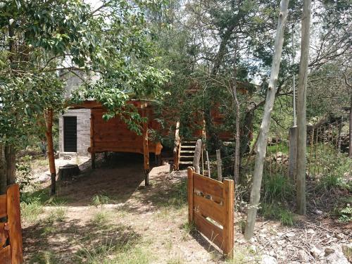 a wooden cabin in the woods with a fence at La Cabañita in Tanti