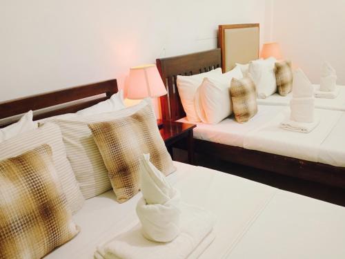 two beds in a hotel room with white and gold pillows at Mariana Condotel in Puerto Princesa City