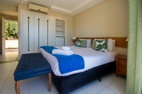 a bedroom with a large bed with a blue bench at Pousada e Spa Villa Mercedes by Latitud Hoteles in Búzios