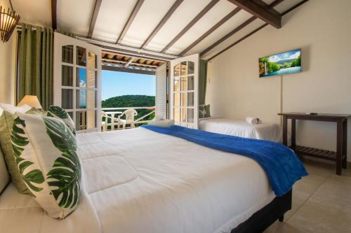 a bedroom with two beds and a balcony at Pousada e Spa Villa Mercedes by Latitud Hoteles in Búzios