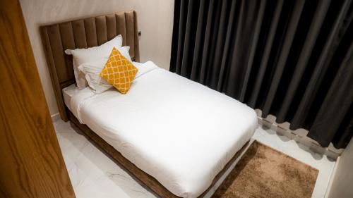 Una cama con una almohada amarilla en una habitación en RESIDENCE MH HOTEL, en Laayoune