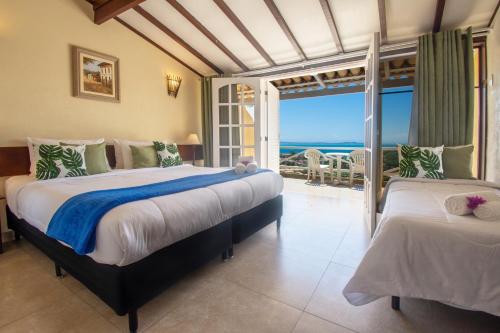 two beds in a room with a view of the ocean at Pousada e Spa Villa Mercedes by Latitud Hoteles in Búzios