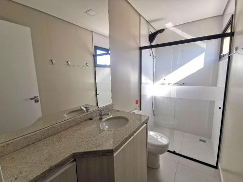 a bathroom with a sink and a toilet and a mirror at Click Apê Prime Foz in Foz do Iguaçu