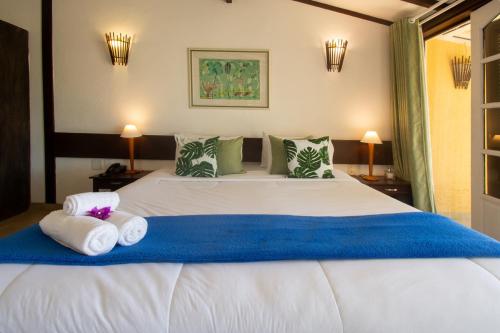 a bedroom with a large white bed with towels on it at Pousada e Spa Villa Mercedes by Latitud Hoteles in Búzios