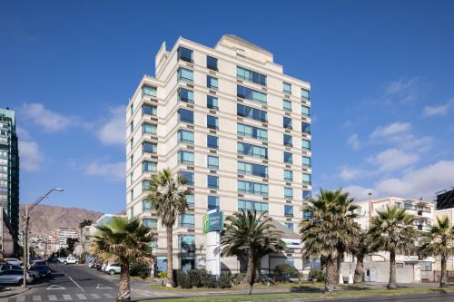 安托法加斯塔的住宿－安託法加斯塔智選假日酒店，一座高大的白色建筑,前面有棕榈树
