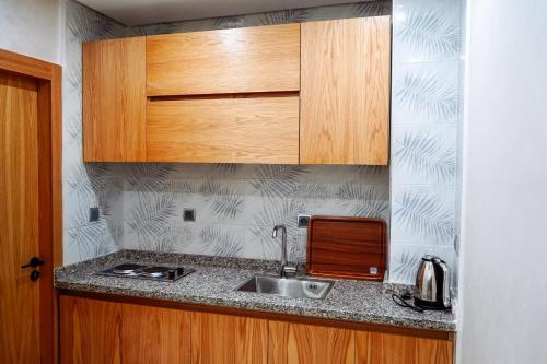 eine Küche mit einer Spüle und Holzschränken in der Unterkunft RESIDENCE MH HOTEL in El Aaiún