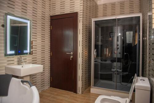 uma casa de banho com um chuveiro, um WC e um lavatório. em Abada Luxury Hotel and Suites em Onitsha