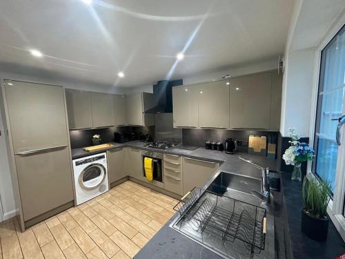a kitchen with a sink and a washing machine at Charming room in stylish house in Milton Keynes