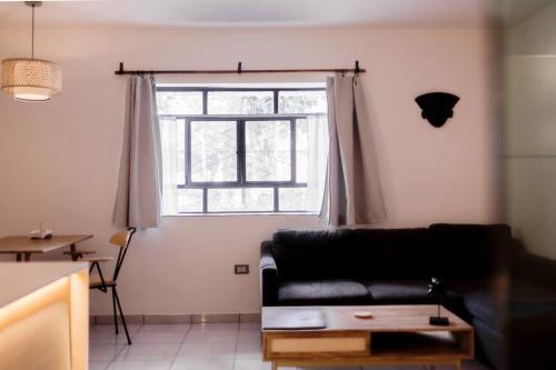 ein Wohnzimmer mit einem schwarzen Sofa und einem Fenster in der Unterkunft Casa Amma - Bhakti in Matehuala