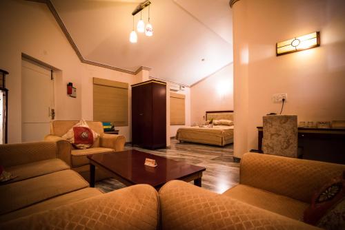 a living room with couches and a table and a bed at Vijayshree Resort, Hampi in Hampi