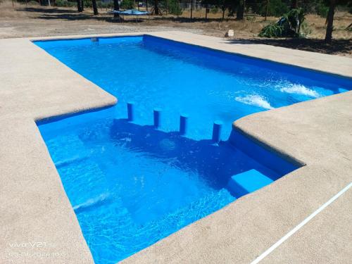 a swimming pool with blue water in a yard at Cabañitas Zelada in Algarrobo