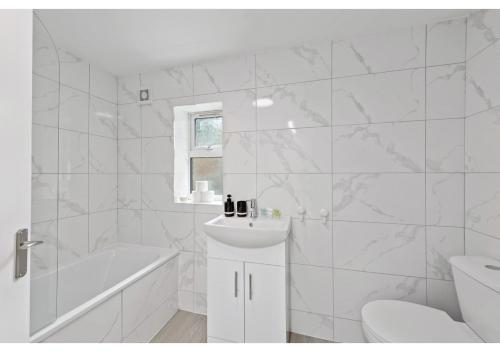 ein weißes Badezimmer mit einem Waschbecken, einer Badewanne und einem WC in der Unterkunft Serenity, Scenery, Shopping, & Sports in London
