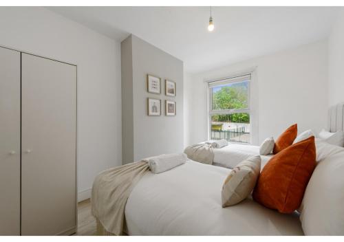 a white bedroom with two beds and a window at Serenity, Scenery, Shopping, & Sports in London
