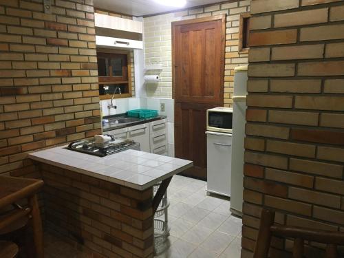 a kitchen with a brick wall and a counter top at Encontro das Águas in Guarda do Embaú