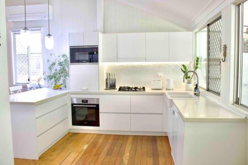 una cocina blanca con armarios blancos y encimeras blancas en Timeless Elegance Executive Home with water views, en Gold Coast