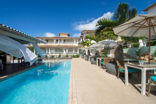 un complejo con una piscina con mesas y sombrillas en Pousada Aroma do Mar by Latitud Hoteles en Búzios
