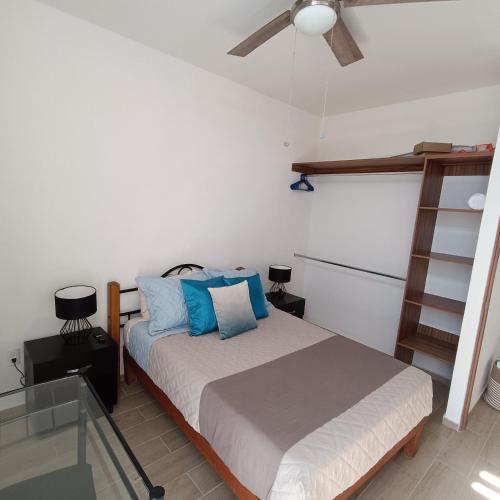 a bedroom with a bed with blue pillows and a ceiling fan at RIBERA DE CHAPALA Suites in Chantepec