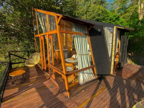 a wooden house with a table and chairs on a deck at NaturalMente Glamping in San Antonio del Tequendama