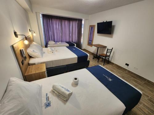 um quarto de hotel com duas camas e uma secretária em HOTEL LUXOTEL PISCO em Pisco