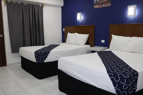 two beds in a hotel room with blue walls at Hotel Tropical in Progreso