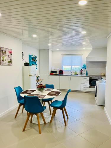 a kitchen with a table and blue chairs at Casa das Courelas in Nordeste