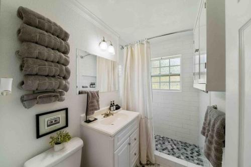 a white bathroom with a sink and a shower at Pet Friendly Riverside Retreat Near Gathering Pl in Tulsa
