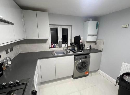 a kitchen with a sink and a washing machine at Double Bedroom in London