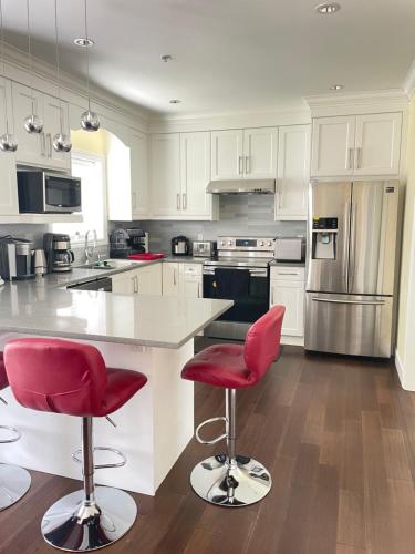 a kitchen with white cabinets and red bar stools at Arbutus Rose House at Vancouver west side in Vancouver