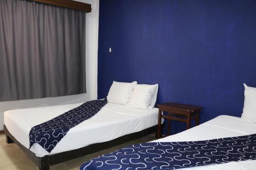 two beds in a room with a blue wall at Hotel Tropical in Progreso