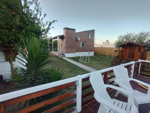 a deck with two white chairs and a house at Atardeceres del Valle in La Bolsa