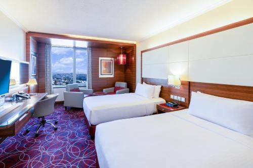 a hotel room with two beds and a desk at Crowne Plaza Amman by IHG in Amman