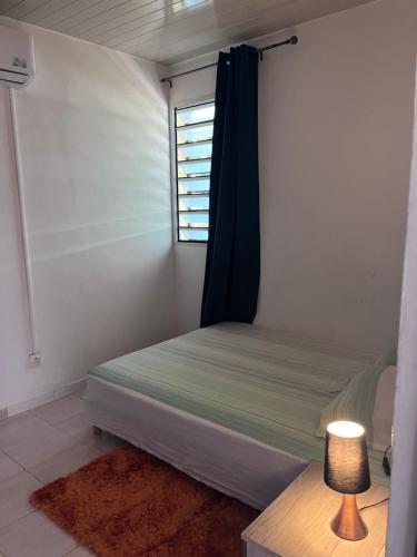 Un dormitorio pequeño con una cama y una ventana. en SIMPLISSIME T4 à KOUROU, en Kourou