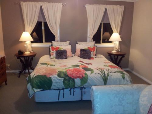 1 dormitorio con 1 cama con colcha de flores y 2 ventanas en Waterview Gardens B&B en Margate