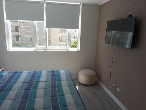 een slaapkamer met een bed en een flatscreen-tv bij Depto. en el centro de Viña in Viña del Mar
