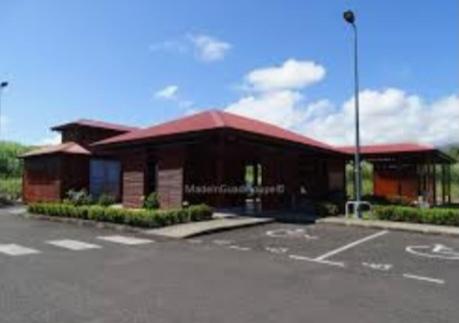 a building with a red roof in a parking lot at Tigili l'Appart Lagon in Capesterre-Belle-Eau
