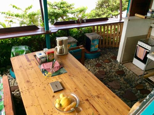 a wooden table with a bowl of fruit on a patio at L'Auberge de Tahiti Iti - Beach hostel in Afaahiti
