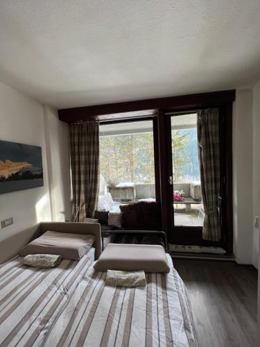 uma sala de estar com duas camas e uma grande janela em Mazzin Raggio di Sole em Campestrin