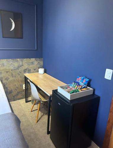 a blue room with a desk and a table with a chair at Kim Casa BH in Belo Horizonte