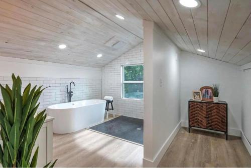 uma casa de banho com uma banheira branca e uma planta em Midtown Masterpiece Whot Tub, Pets Welcome! em Tulsa